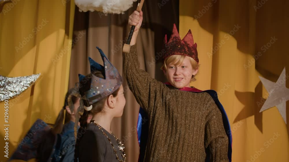 Group of cheerful diverse boys and girls wearing costumes playing on school theatre stage