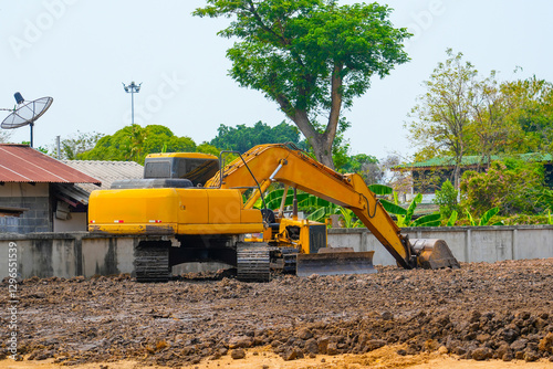 Excavator on the ground of a construction site with a raised bucket rural landscape around photo