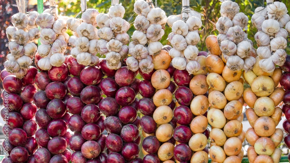 Farm onions and garlic braided in braids on a stall for sale on a sunny summer day. Organic farming Farm onions and garlic braided in braids on a stall for sale on a sunny summer day. Organic farming