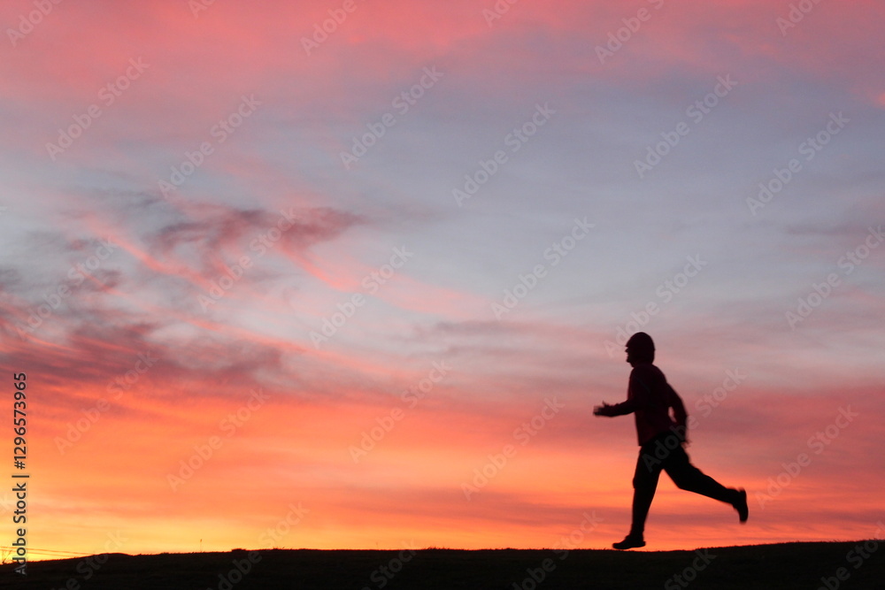 silhueta de pessoa praticando exercícios ao ar livre no nascer do sol, com céu alaranjado ao fundo silhueta de pessoa praticando exercícios ao ar livre no nascer do sol, com céu alaranjado ao fundo