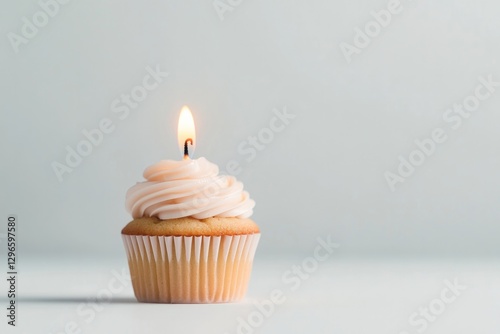 minimalist cupcake with single lit candle centered on smooth white surface under bright diffused light photo