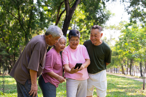 Group of happy Senior Retirement Using Smartphone and laughing outdoors at the park after a workout and spending time together, concepts about the elderly, seniority, and wellness aging