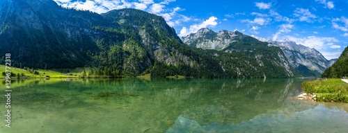 Stunning panorama view of Konigssee Lake with peak Watzmann and Bavarian alps with reflections in Berchtesgaden national park on a sunny summer day with blue sky and cloud, Schoenau, Bavaria, Germany