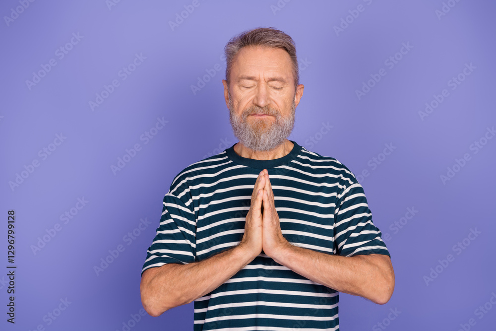 Elderly man with clasped hands meditating with a calm expression in front of a violet background Elderly man with clasped hands meditating with a calm expression in front of a violet background