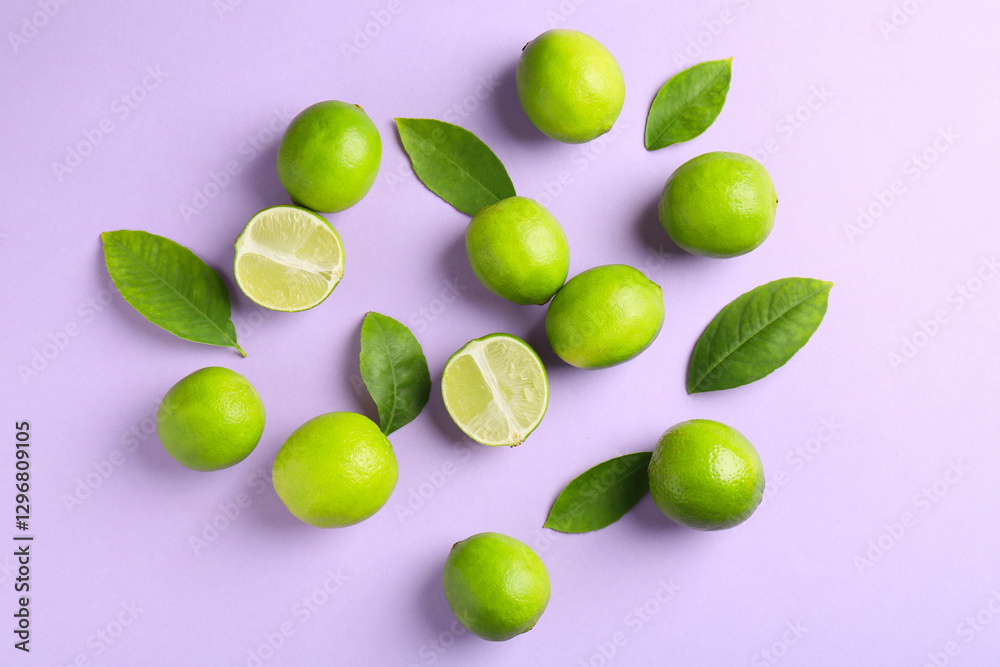 Fototapeta premium Fresh limes and leaves on violet background