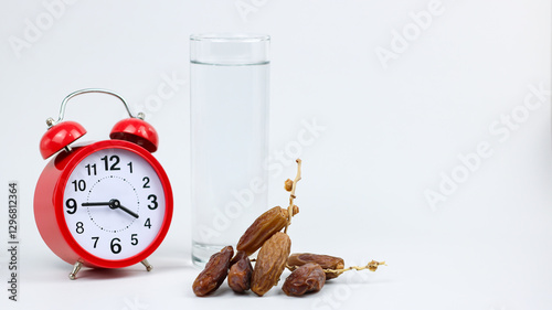 Dates fruits on wooden bowl and drinking water - isolated on white background. Suhoor concept with alarm clock photo