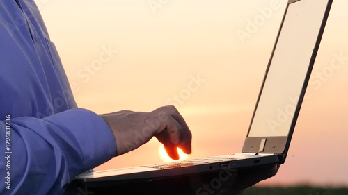 Talented farmer types on laptop working in corn field closeup. Competent peasant grows corn with computer technology at countryside. Efficient agronomist saves data on laptop examining corn field