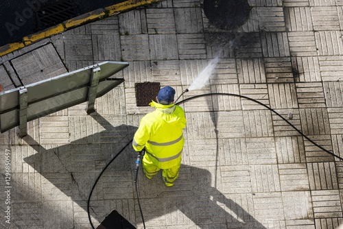 Worker cleaning a street sidewalk with high pressure water jet machine