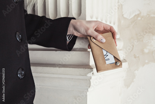 Female hand holding leather card holder in classic urban setting
