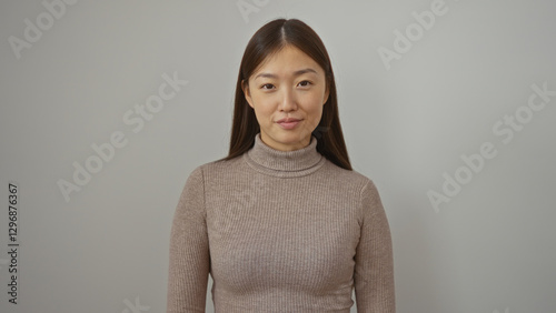 Woman with long hair smiling softly stands against a neutral white background exuding confidence and beauty with an elegant and simple style.