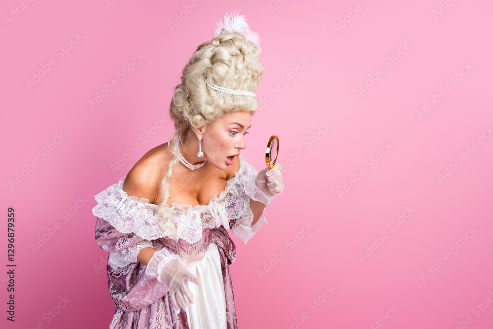Fototapeta premium Elegant female in a historical costume observes with a magnifying glass on a vibrant pink background
