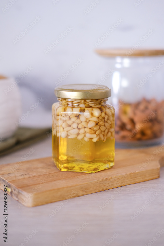 Cedar nuts with honey in glass jars on white wooden boards. Cedar nuts with honey in glass jars on white wooden boards.