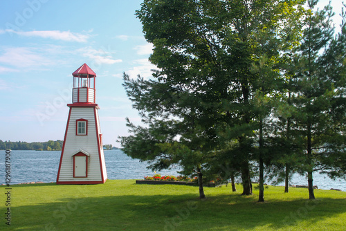 Decorative white and red lighthouse structure on the grassy shoreline of Gananoque, Ontario photo