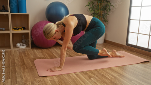 Woman exercising in gym performing yoga pose on mat with fitness equipment displayed in modern interior gym center emphasizing health commitment and wellness focus.