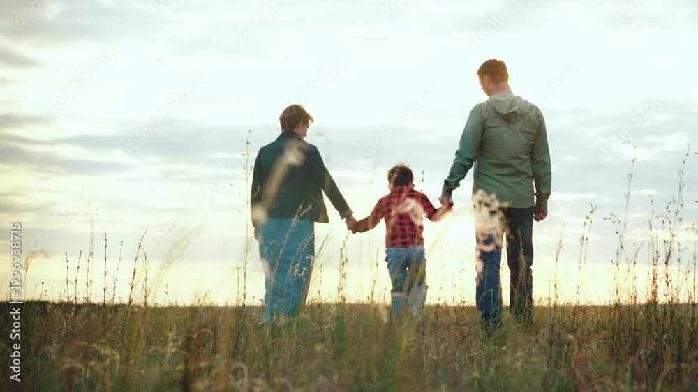 Happy family finds joy in leisurely walk across field savouring moments weather brings. Family holds hands symbolising strong familial bond unites. Family vacation time for active experiences Happy family finds joy in leisurely walk across field savouring moments weather brings. Family holds hands symbolising strong familial bond unites. Family vacation time for active experiences