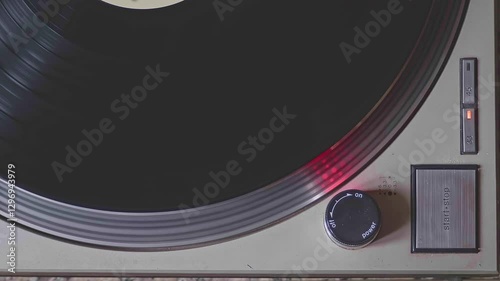 Close-up shot of a turntable being turned off. The platter slows to a halt, and the needle lifts from the vinyl record.