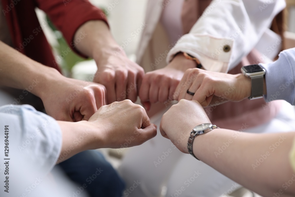 Unity concept. People holding fists together indoors, closeup