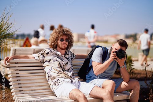Two Tourists Relaxing on a Bench While Exploring a Mediterranean Tourist City. photo