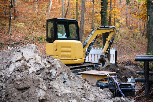 Obraz na płótnie A Compact Loader in a Beautiful Autumn Forest Landscape Perfect for Construction Work w salonie