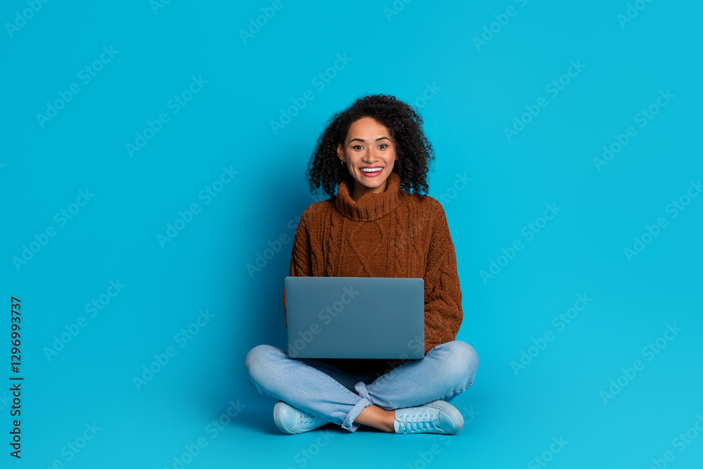 Naklejka premium Smiling young woman with laptop on blue background presenting casual and trendy lifestyle