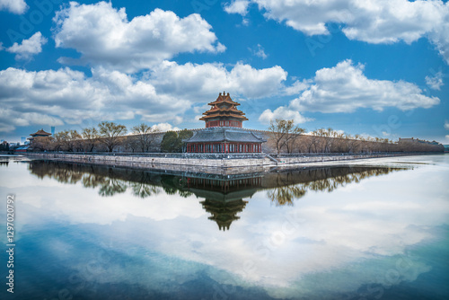 The Corner Tower of the Palace Museum in China under the blue sky and white clouds, together with its reflection in the water