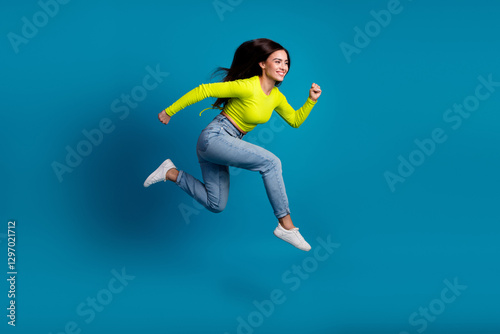 Wallpaper Mural Energetic young woman in casual outfit happily leaping against a vibrant blue background Torontodigital.ca