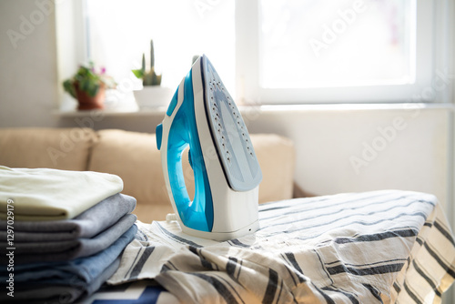 Electric iron and pile of clothes on ironing board