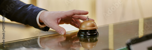 Website banner with unrecognizable male hand ringing reception bell in hotel