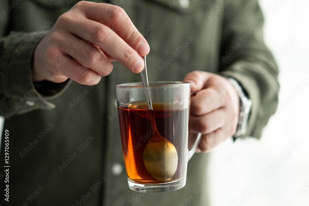Person Stirring Hot Tea in a Transparent Mug with a Spoon Person Stirring Hot Tea in a Transparent Mug with a Spoon