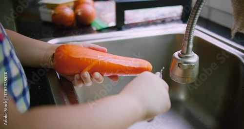 Close-Up of Hands peeling a Fresh carrot over a kitchen sink, showcasing fresh produce preparation in a home kitchen environment