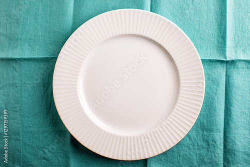 Empty white plate on folded aqua linen overhead
 photo