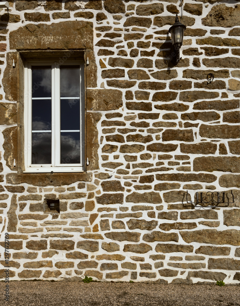 Fototapeta premium Rustic stone wall with irregular brown rocks and white mortar, creating a textured architectural background.