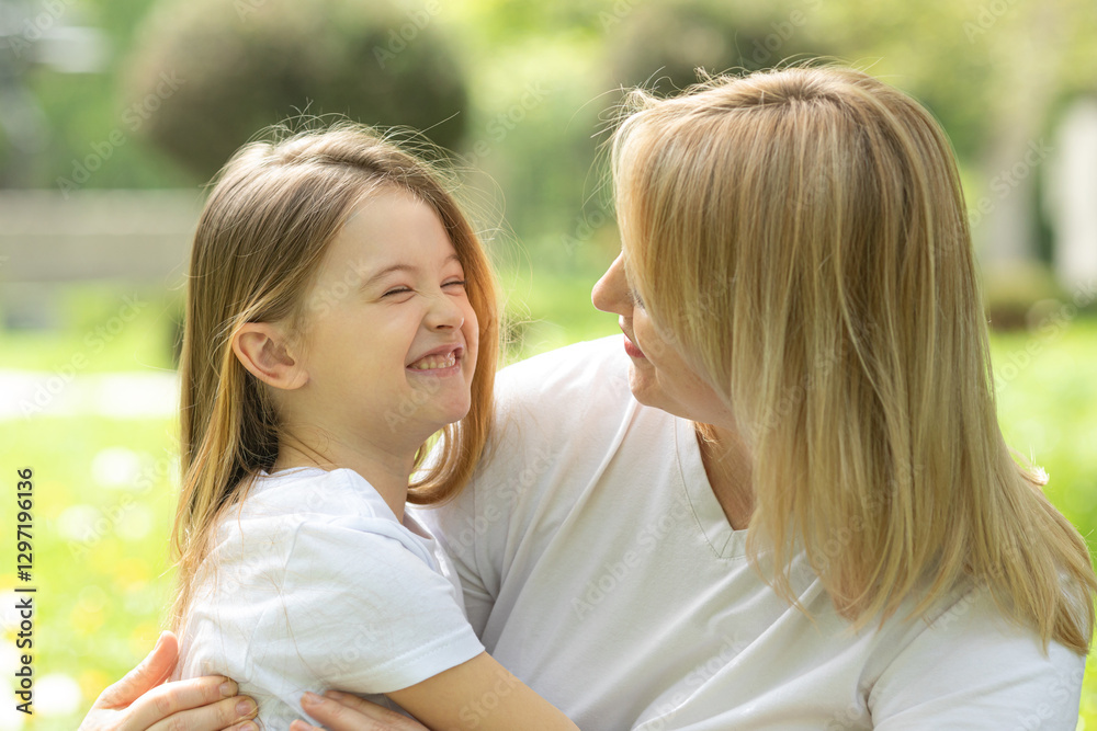 Happy young mother with her daughter in white t-shirts hugging at park. Laughing woman having fun with her little child outdoor. Family and love concept. High quality photo. Copy space Happy young mother with her daughter in white t-shirts hugging at park. Laughing woman having fun with her little child outdoor. Family and love concept. High quality photo. Copy space