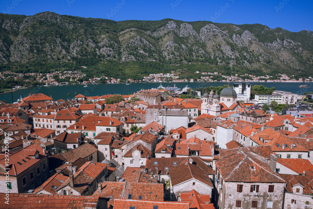 Panoramic view to Kotor old town with old architecture in the foreground and water and mountain in the background, Montenegro Panoramic view to Kotor old town with old architecture in the foreground and water and mountain in the background, Montenegro