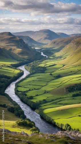 River flows through green valley in hilly landscape. Cloudy sky above mountain range with green fields and natural light creates scenic view.