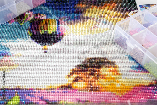 Close-up of a diamond painting and the tools needed to assemble it. Art therapy concept.