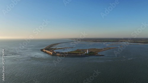 Wide aerial drone shot of Hurst Point Lighthouse and the historic Hurst Castle on a long peninsula sticking into the Solent south of Lymington, England