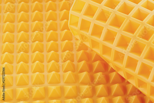 Close-up shot of a yellow silicone mold for cookies. Empty silicone baking mat is isolated on a white background. Front view.