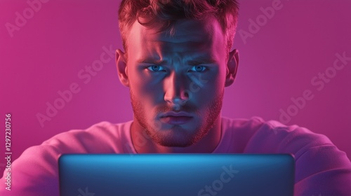 Intense focus of a young man working on a laptop with vibrant pink and blue lighting effects