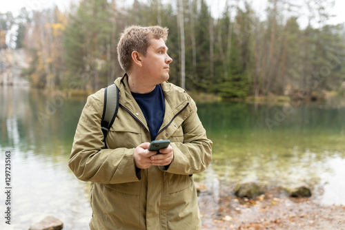Travel backpacker standing with phone near the majestic lake. Travel, adventure. Concept of an active lifestyle. High quality photo