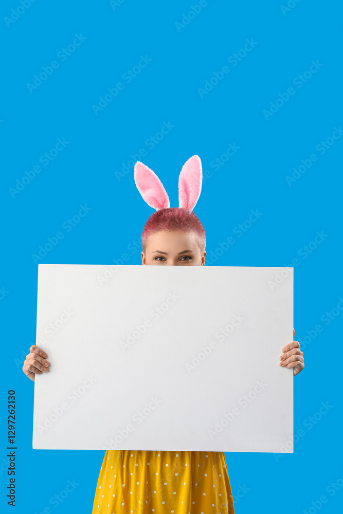 Obraz premium Young woman with bunny ears and blank poster on blue background. Easter celebration