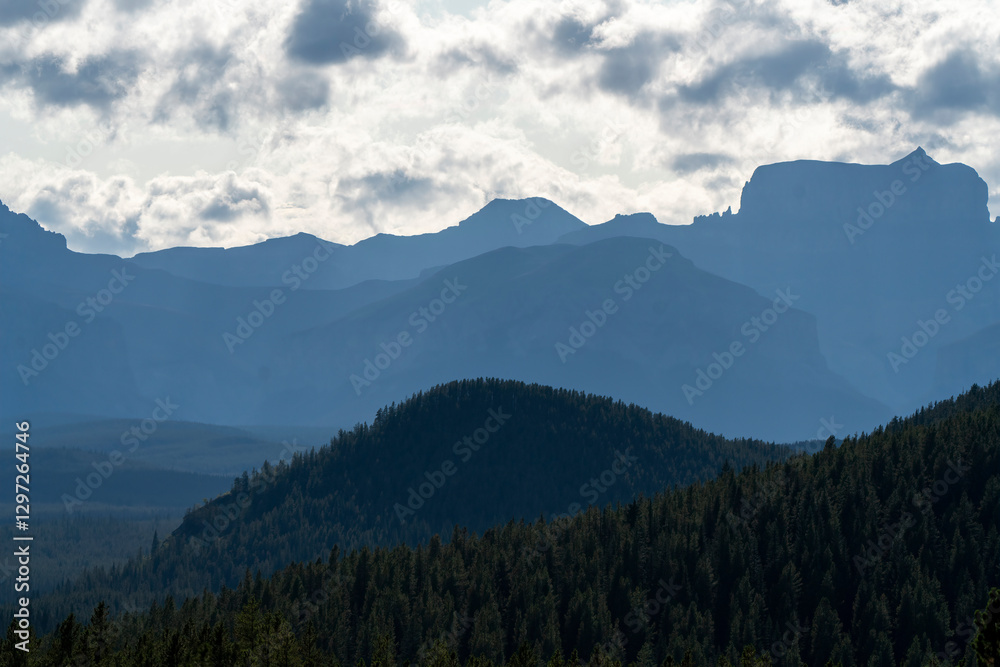 Obraz premium Layers of pine forest and mountains filling the horizon under cloudy sky