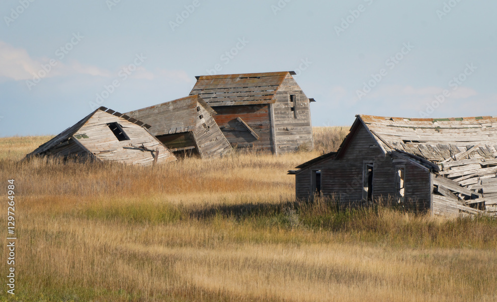 Abandoned farm houses crumbling in a field of prairie grass Abandoned farm houses crumbling in a field of prairie grass