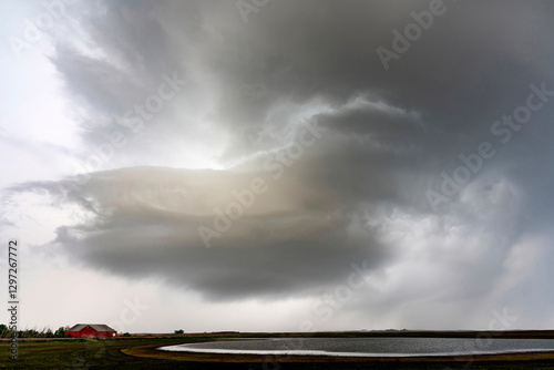 Dramatic supercell storm clouds gathering over farmland