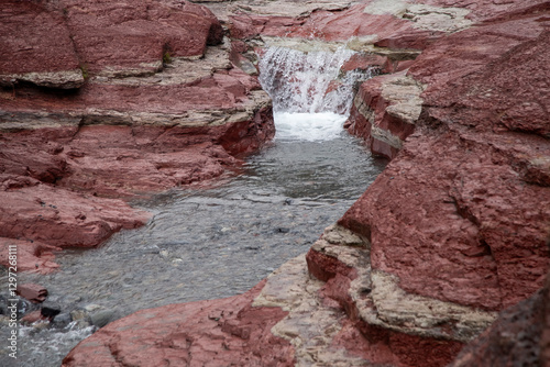 Obraz na płótnie Red rock canyon waterfall flowing through colorful sedimentary rock formations w salonie