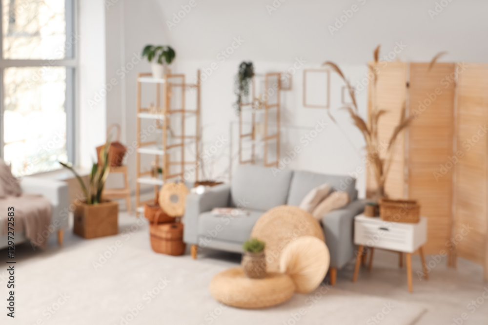 Obraz premium Interior of stylish light living room with grey sofa, braided baskets, coffee table and pampas grass, blurred view