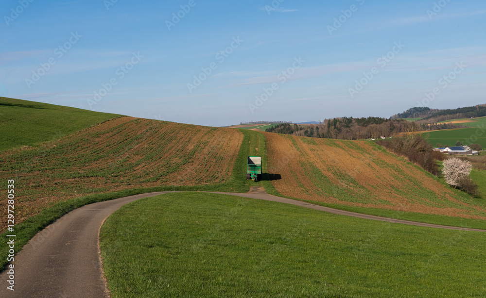 Naklejka premium Scenic countryside landscape with rolling hills and winding road under clear blue sky