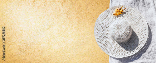 Obraz na płótnie Top view of a beach hat with towel and seashell on the sand under the hot summer sun, horizontal banner. Concept of sandy beach holiday, flat lay, background with copy space for text w salonie