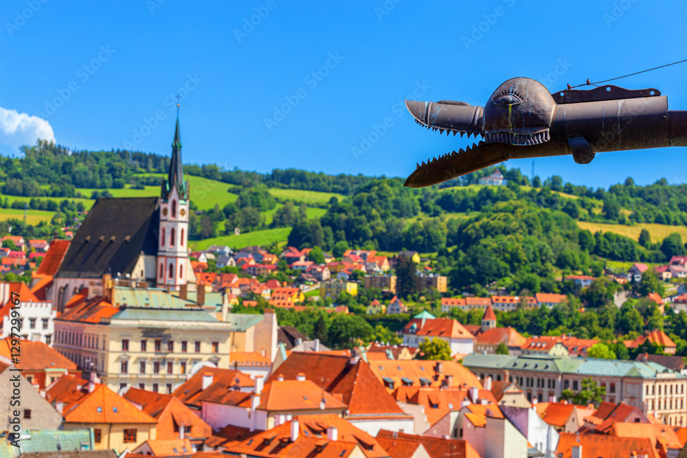 Summer cityscape - close-up view of metal rain gutter in dragon shape against the backdrop of the Old Town of Cesky Krumlov, Czech Republic