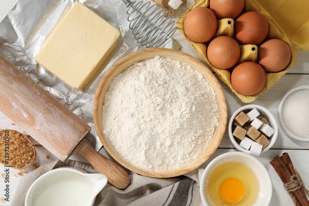 Rolling pin and ingredients for dough on white wooden table, flat lay
